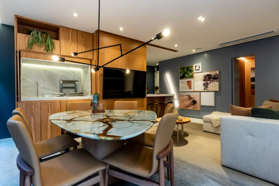 Mesa de jantar em pedra no decorado de 90 m², com a sala e a TV ao fundo
